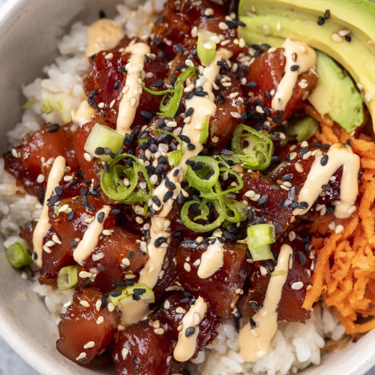 Vibrant, sushi-grade tuna cubes mingle with crisp cucumber and julienned carrot in a colorful bowl, garnished with edamame, pickled ginger, and nori strips. Spicy Tuna Poke Bowl