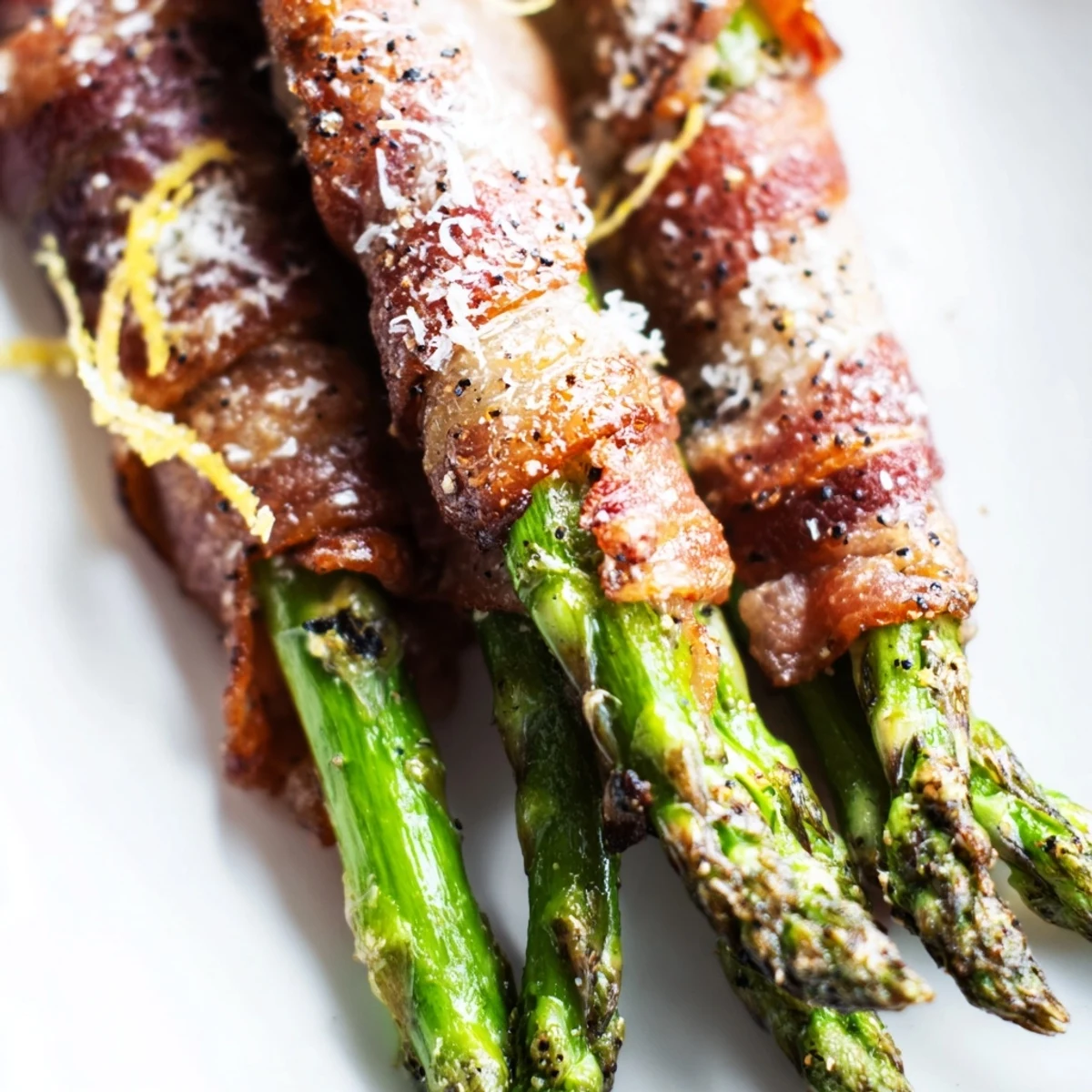 Freshly roasted Crispy Beef Bacon Wrapped Asparagus Bundles served hot on a platter, garnished with lemon zest for a bright finish.