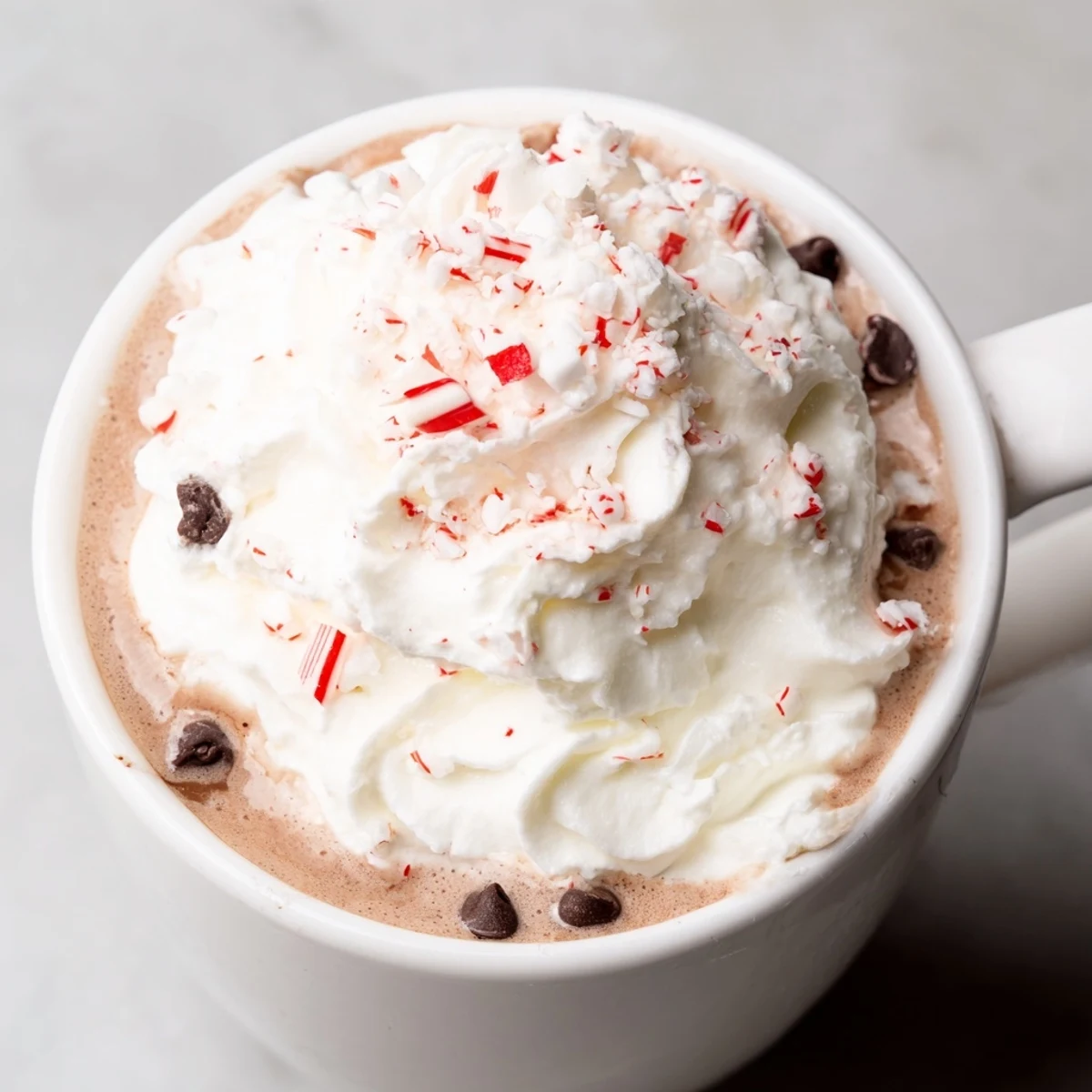 Steamy peppermint hot cocoa topped with fluffy whipped cream in a rustic mug.