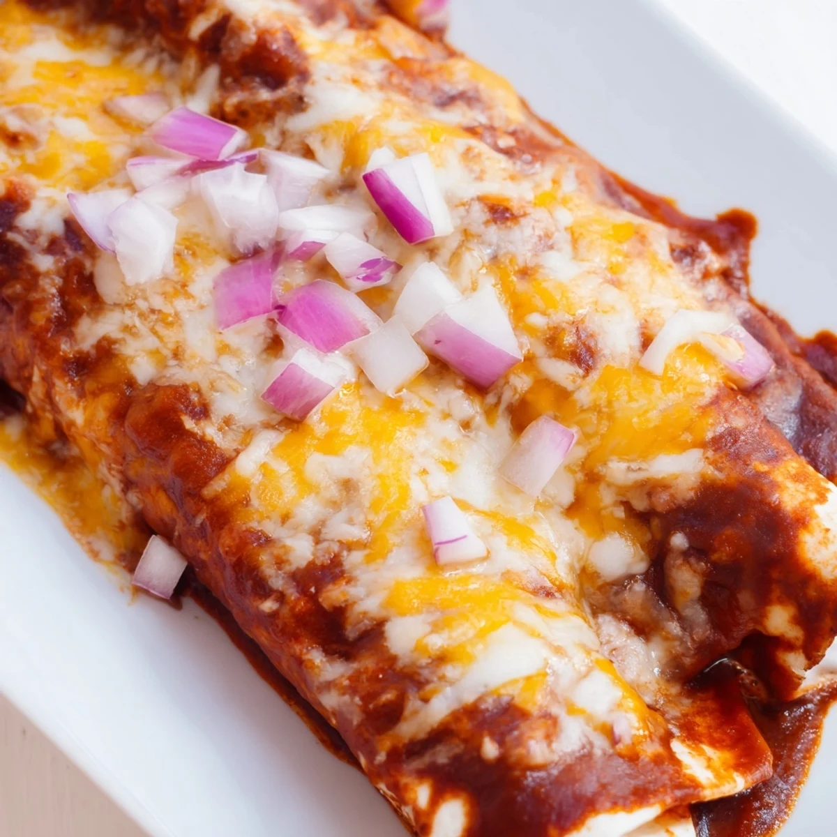 Ground beef and onion filling wrapped in soft tortillas, smothered in a rich red enchilada sauce and topped with fresh cilantro.