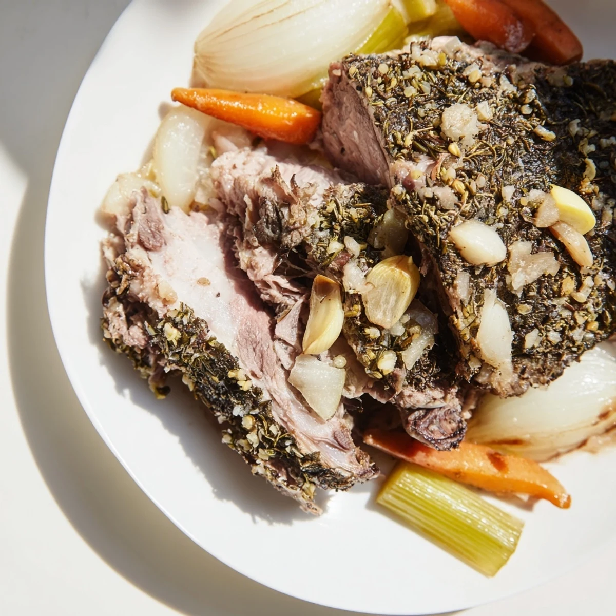 Slow Roasted Lamb Shoulder with Herbs sits on a platter, glistening with golden brown skin, rosemary sprigs, and roasted vegetables.