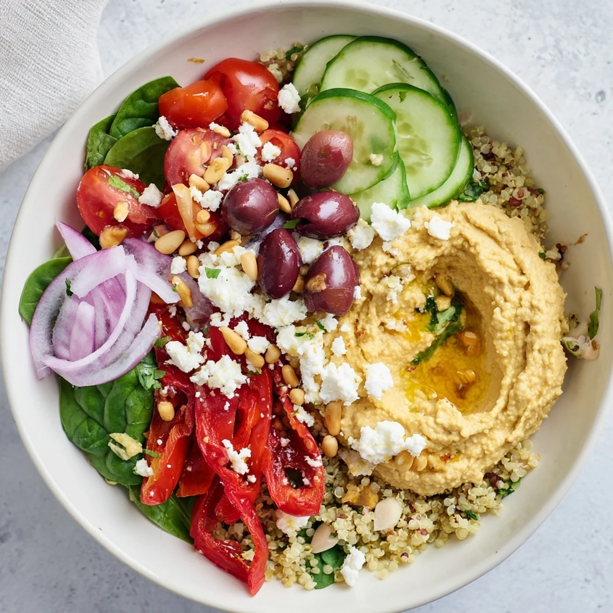Fresh Mediterranean Hummus Bowl topped with feta, olives, and pine nuts on a rustic wooden table. 