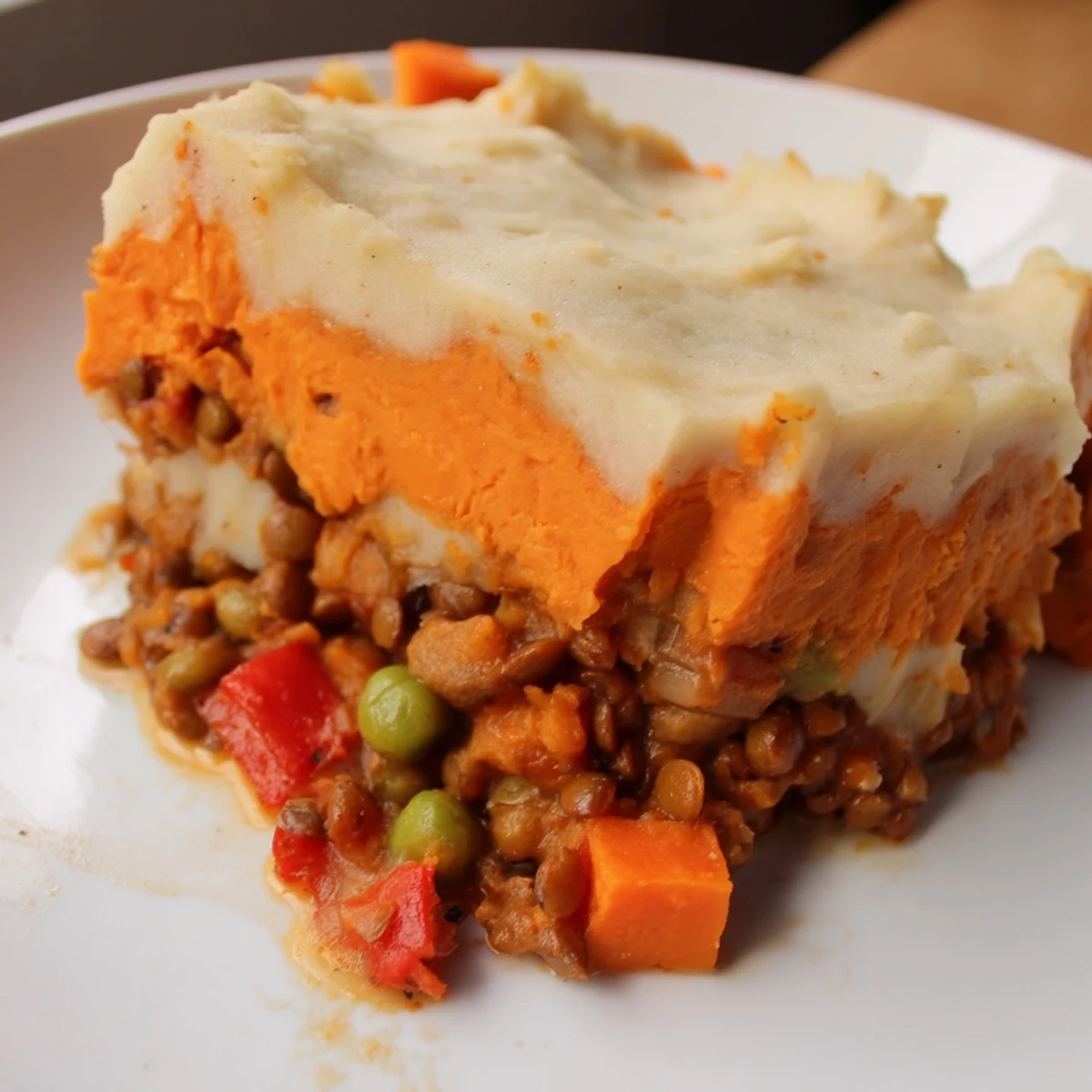 A close-up shows the hearty Vegan Lentil and Sweet Potato Shepherds Pie fresh from the oven, bubbling in a ceramic dish.