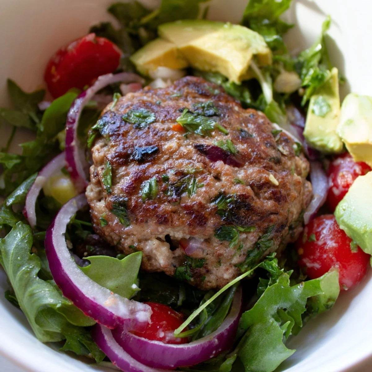 Gluten-free Turkey Burger Salad Bowl with golden-brown turkey patty on a bed of mixed greens, topped with sliced cucumber, tomatoes, and a drizzle of creamy dressing.