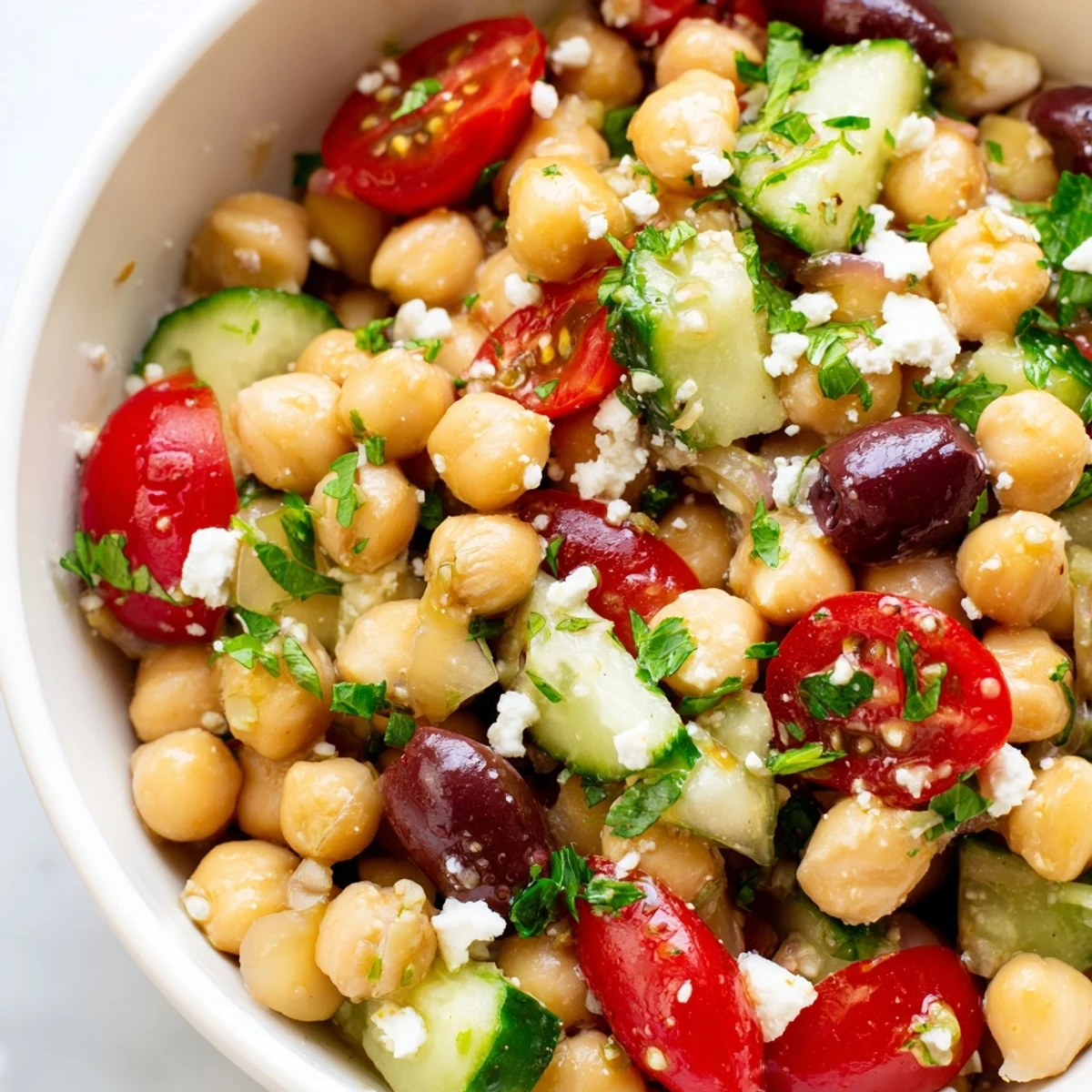 Fresh Mediterranean Chickpea Salad with lemon vinaigrette, featuring crisp cherry tomatoes, cucumbers, and colorful red bell peppers in a bright white bowl.  