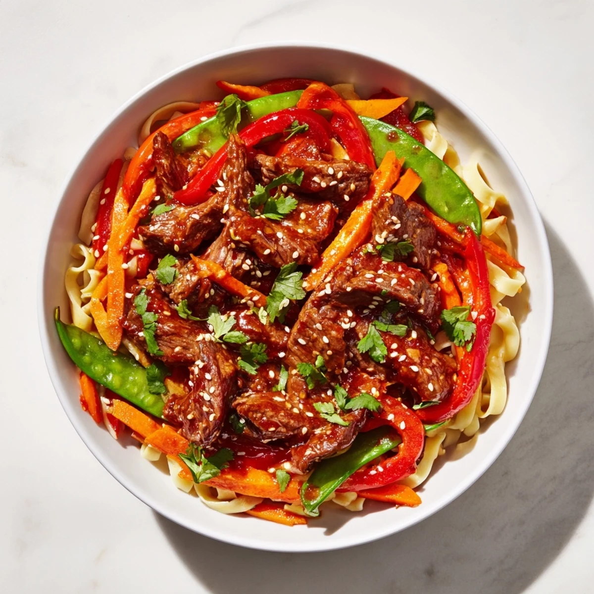 A close-up of Spicy Beef Noodles with Vegetables, featuring tender beef strips, crisp bell peppers, and carrots coated in a glossy red chili sauce.
