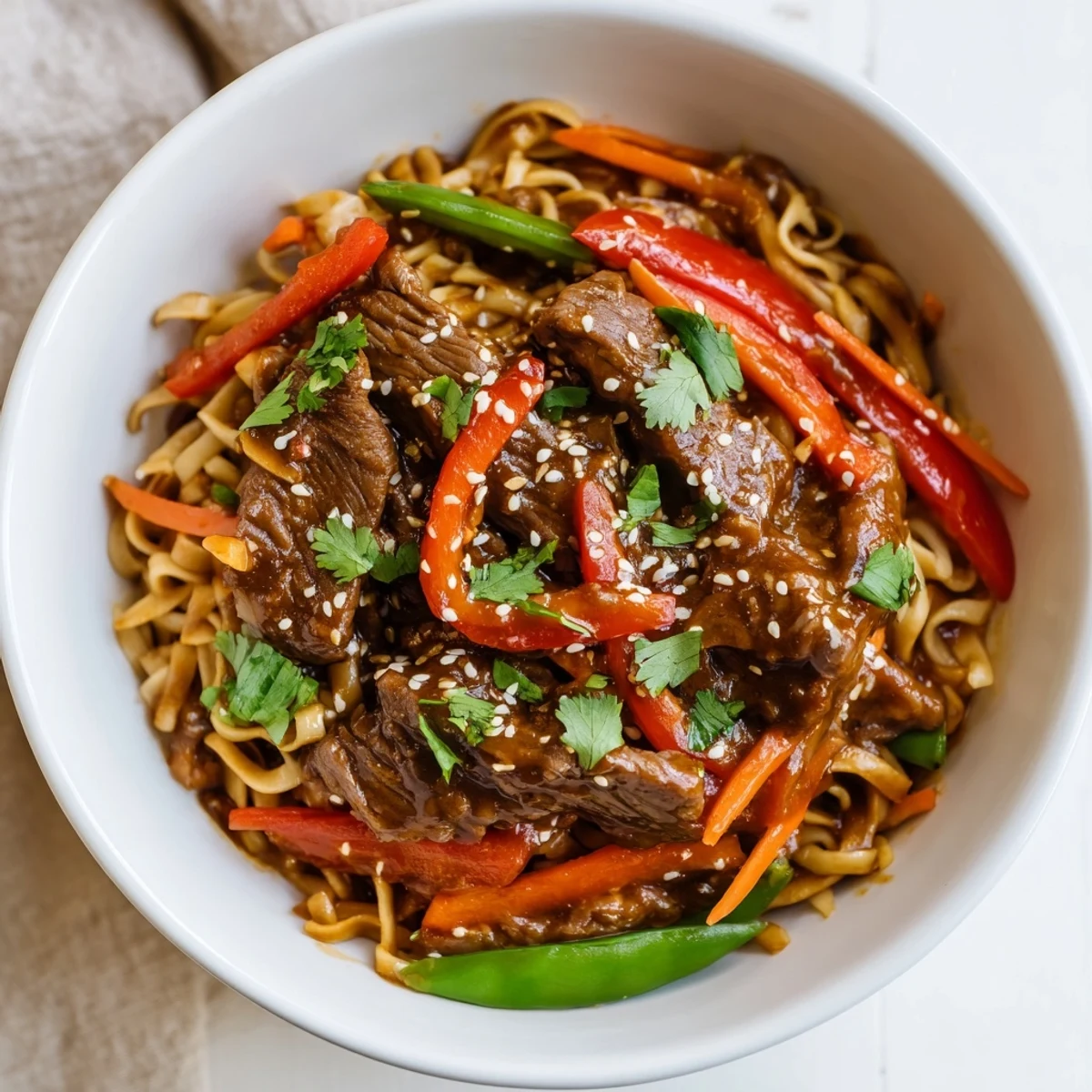 Steam rises from a skillet of Spicy Beef Noodles with Vegetables, stir-fried with garlic and ginger for a fragrant, quick weeknight dinner.