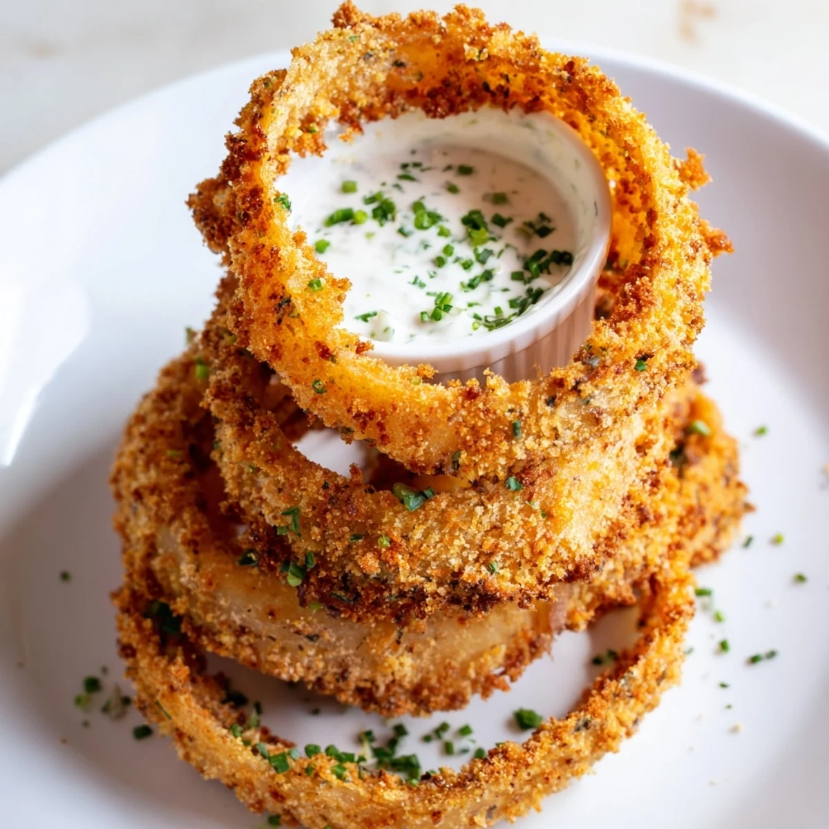 A bowl of Crispy Baked Onion Rings with Ranch served alongside a frosty lager, a perfect game-day appetizer.