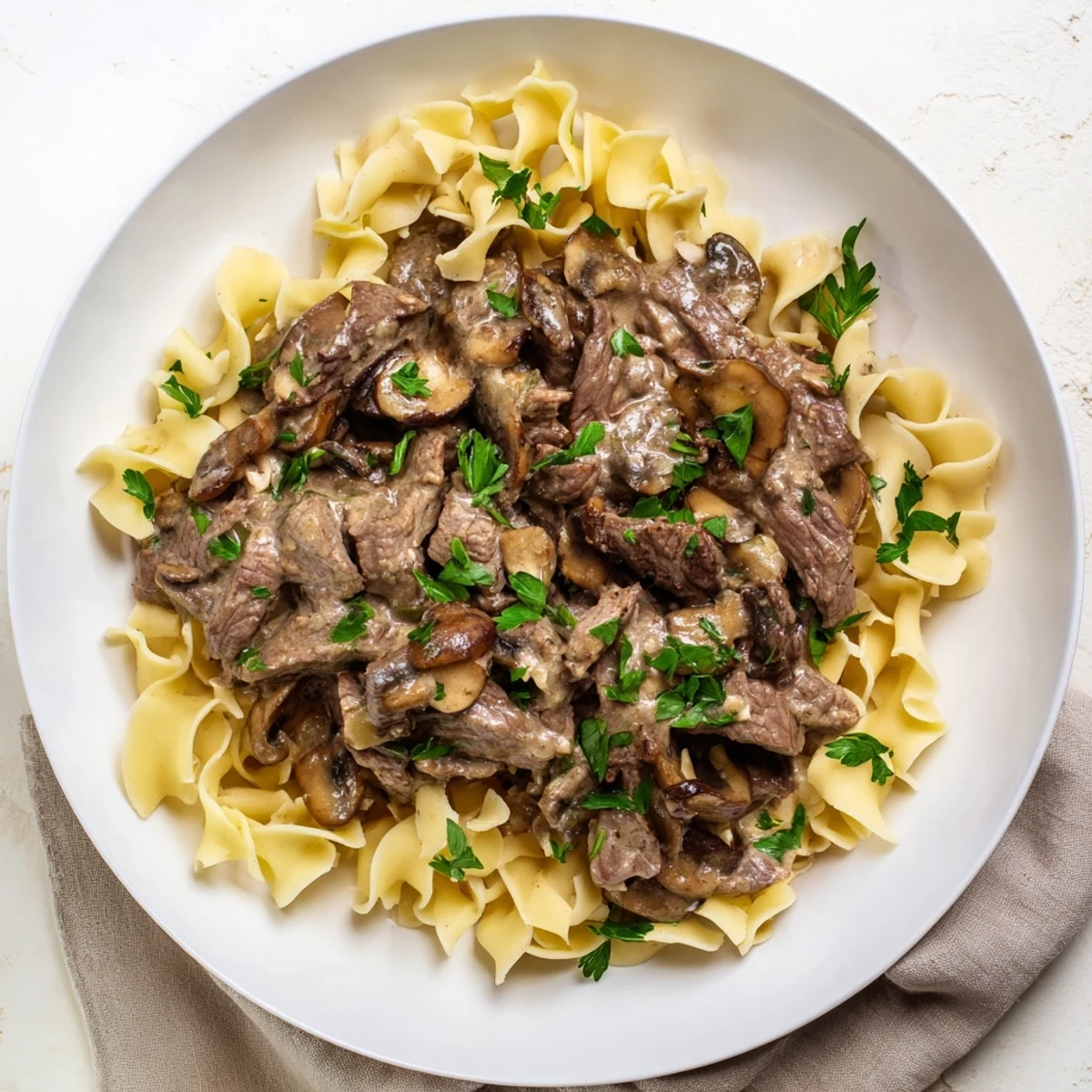 Sizzling strips of beef in creamy mushroom sauce over wide egg noodles for Beef Stroganoff.