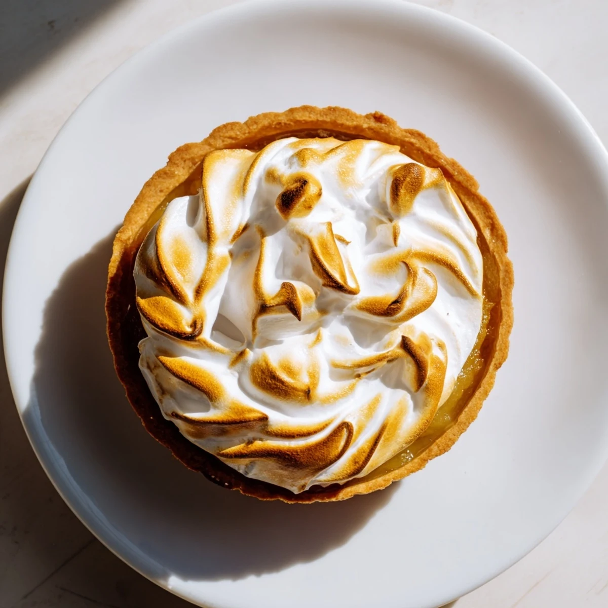 Slice of Irish Apple Amber Tart with Meringue Top served warm with a dollop of whipped cream and spoon.