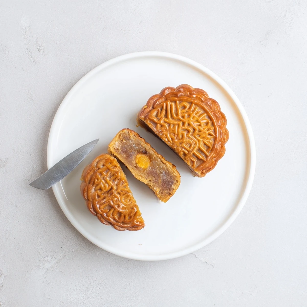 Traditional mooncakes are arranged on a ceramic plate, showcasing their smooth crust and decorative imprint for Mid-Autumn Festival.