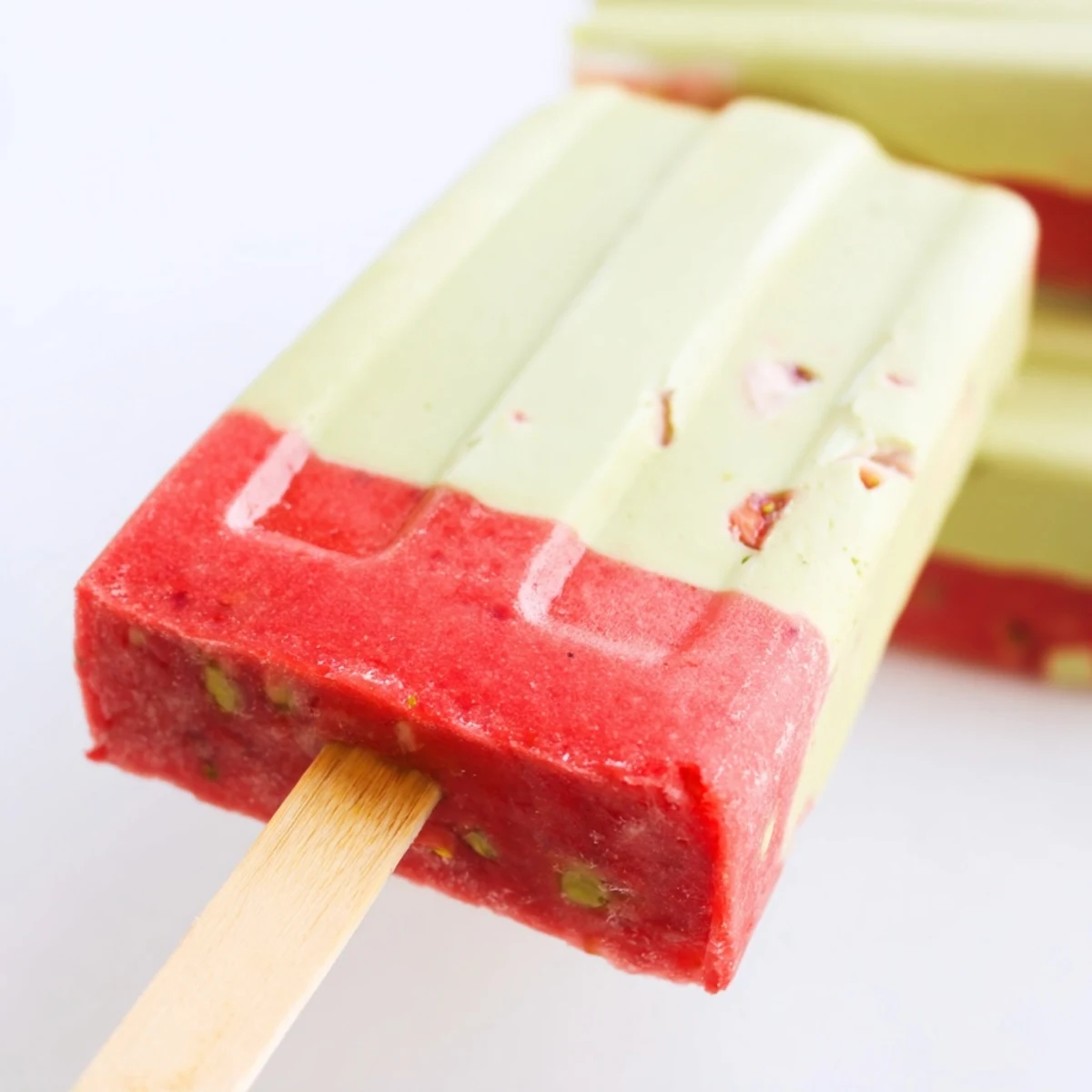 Enjoy these dairy-free Strawberry Matcha Latte Popsicles with a colorful ombre look, served on a sunny patio for a cool treat.