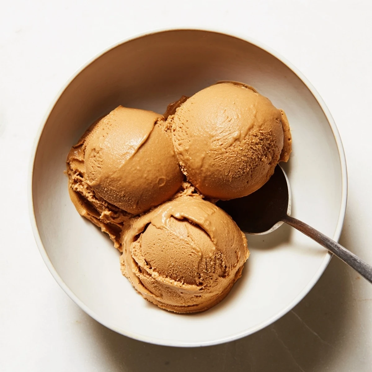 A close-up of homemade Hojicha Ice Cream in a waffle cone, showcasing its rich, brown hue.  