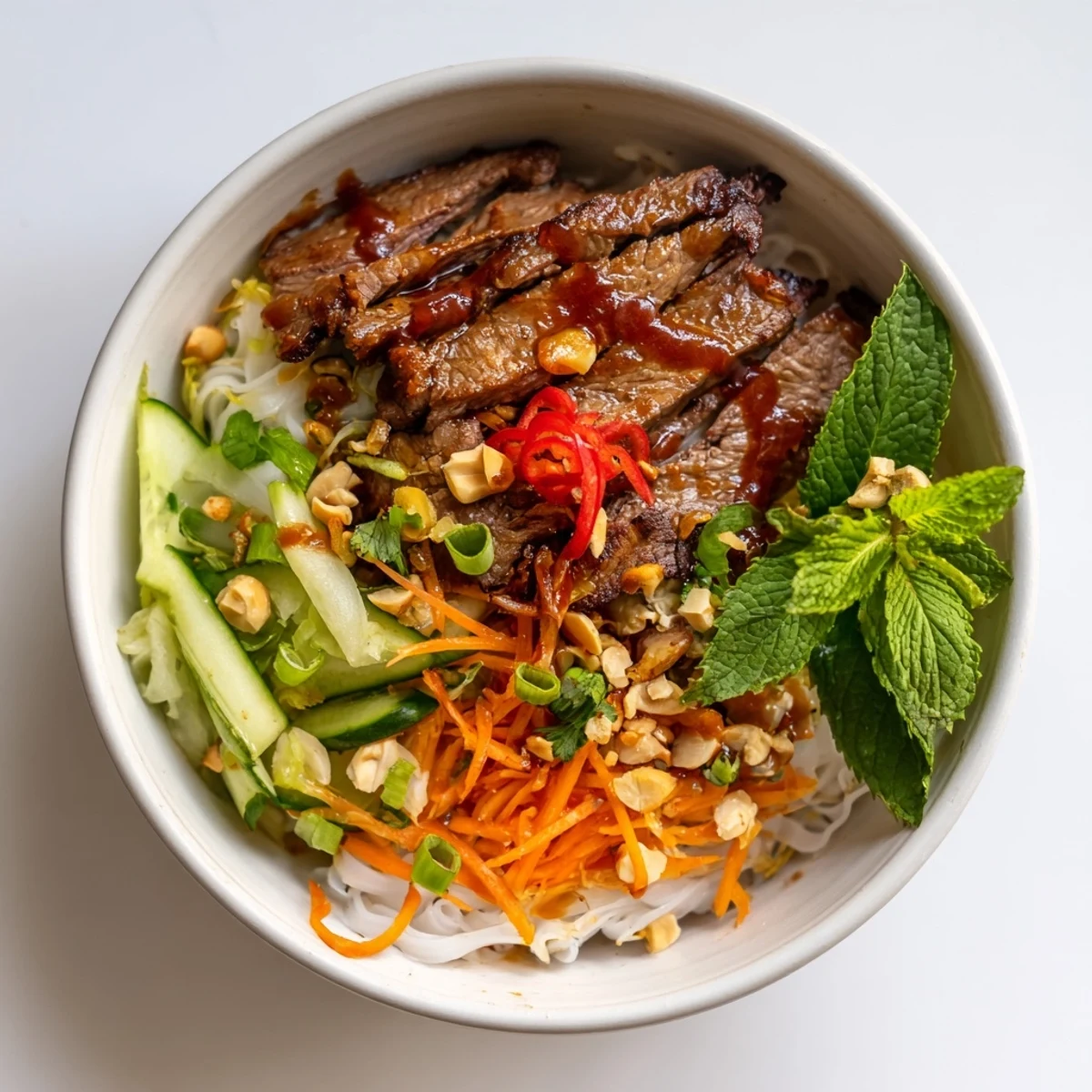 Overhead view of vibrant Bun Bo Xao salad, with julienned carrots, cucumber, and tender beef ready to enjoy.