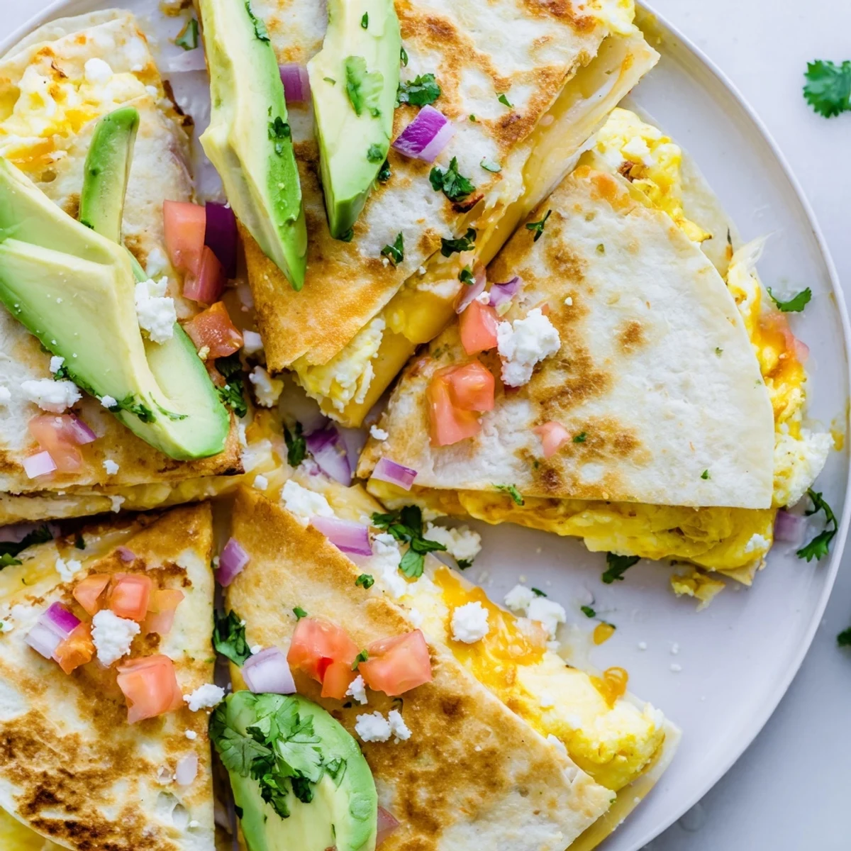 Sizzling hot quesadillas are cut into wedges, revealing layers of fluffy eggs, ripe avocado slices, and spicy jalapeños paired with fresh cilantro and onion.