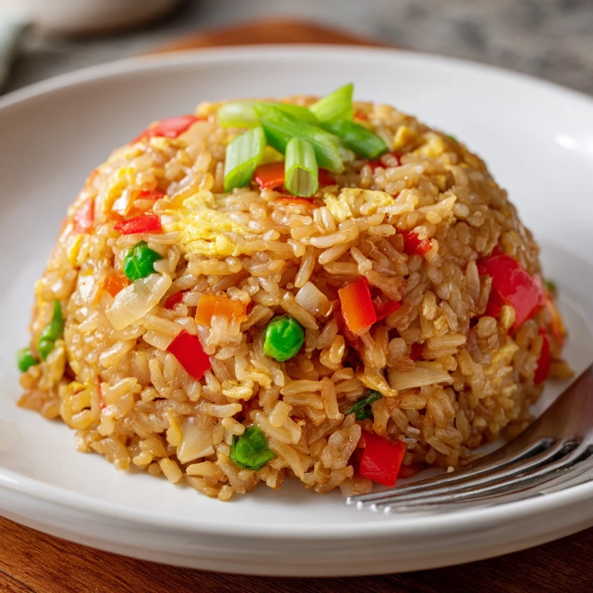 Freshly cooked Fried Rice served in a white bowl with chopsticks, garnished with extra green onions.