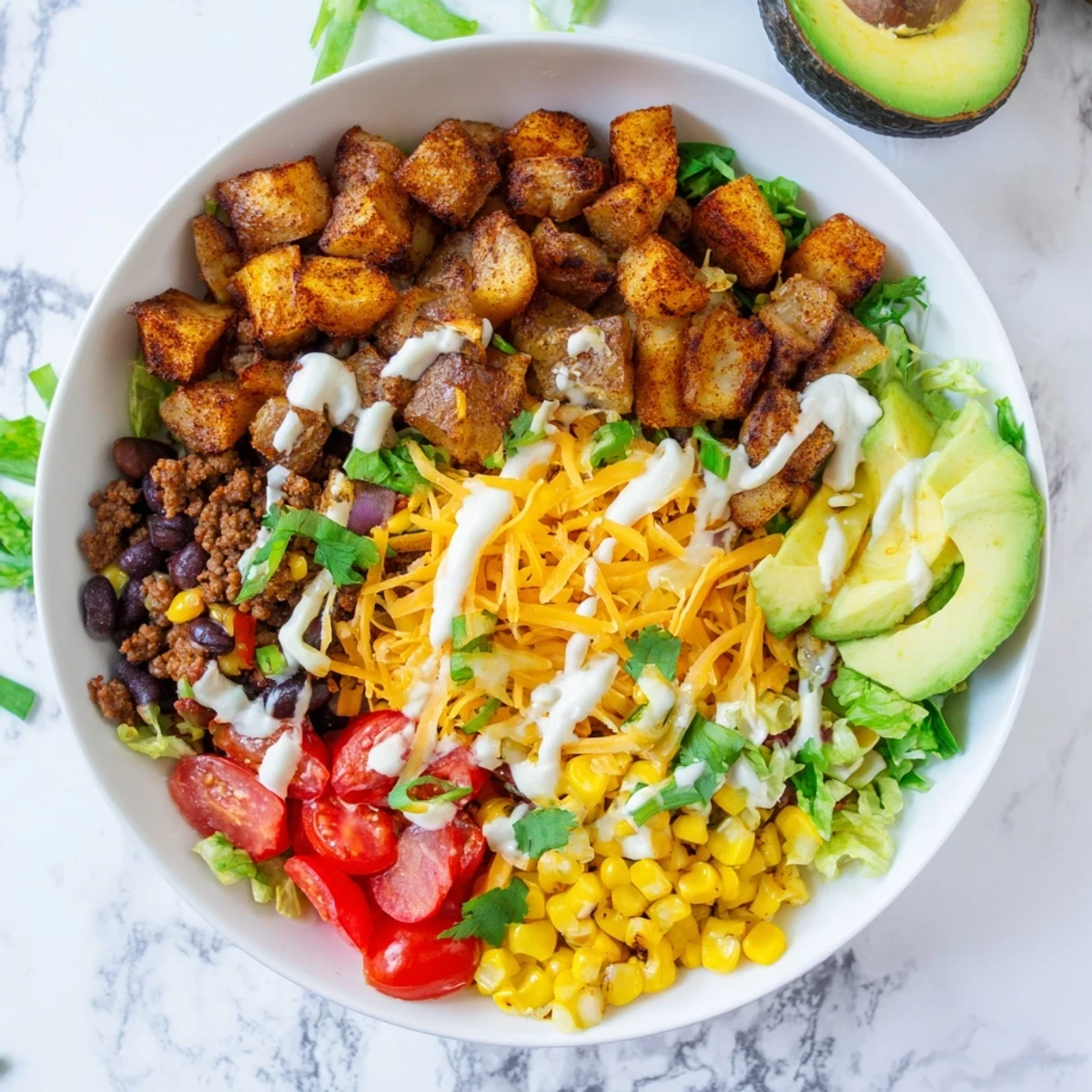 Loaded Potato Taco Bowl is drizzled with zesty lime crema and sprinkled with green onions and cilantro.