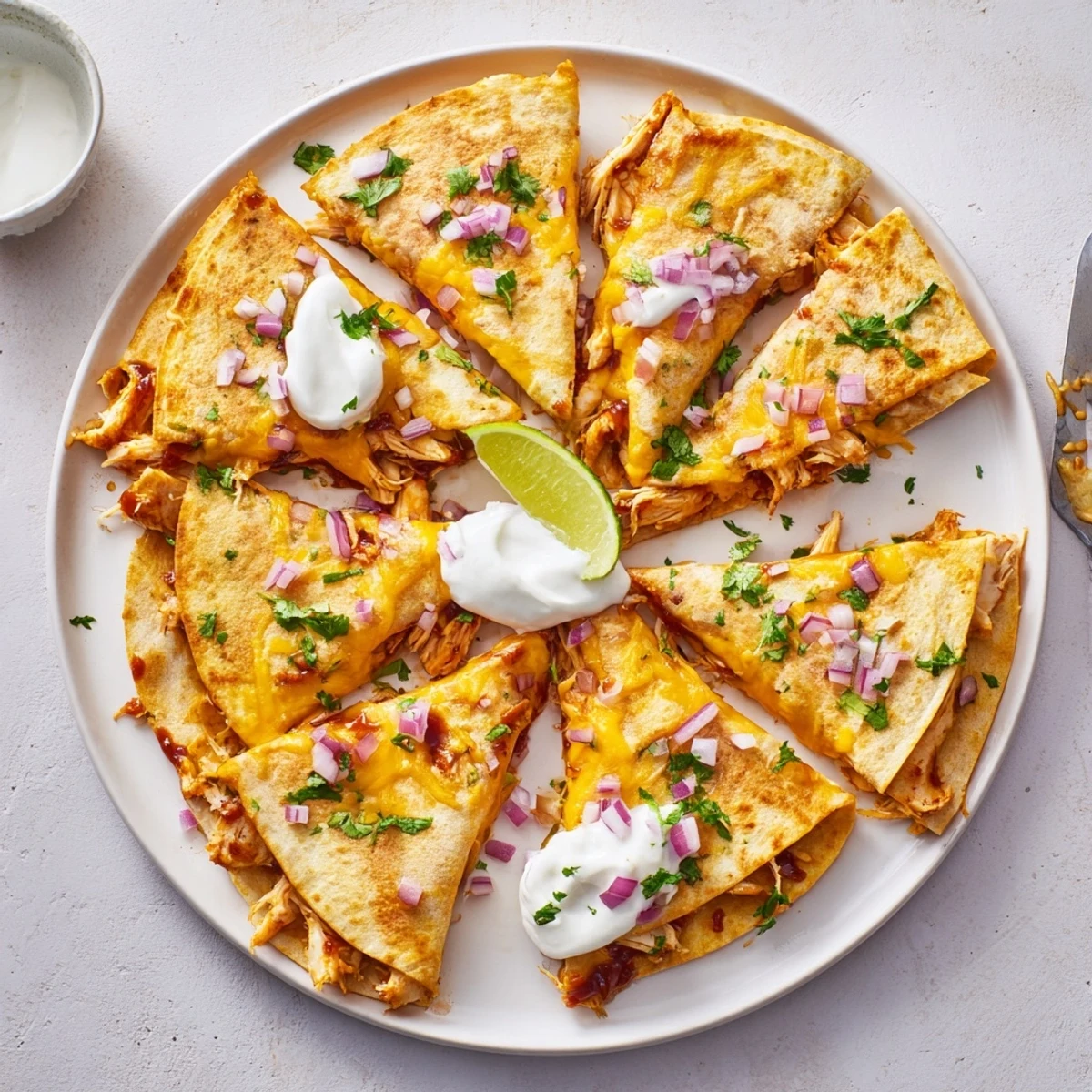 A serving of Hot Honey BBQ Chicken Quesadillas with lime wedges, showcasing smoky BBQ sauce and tender shredded chicken.