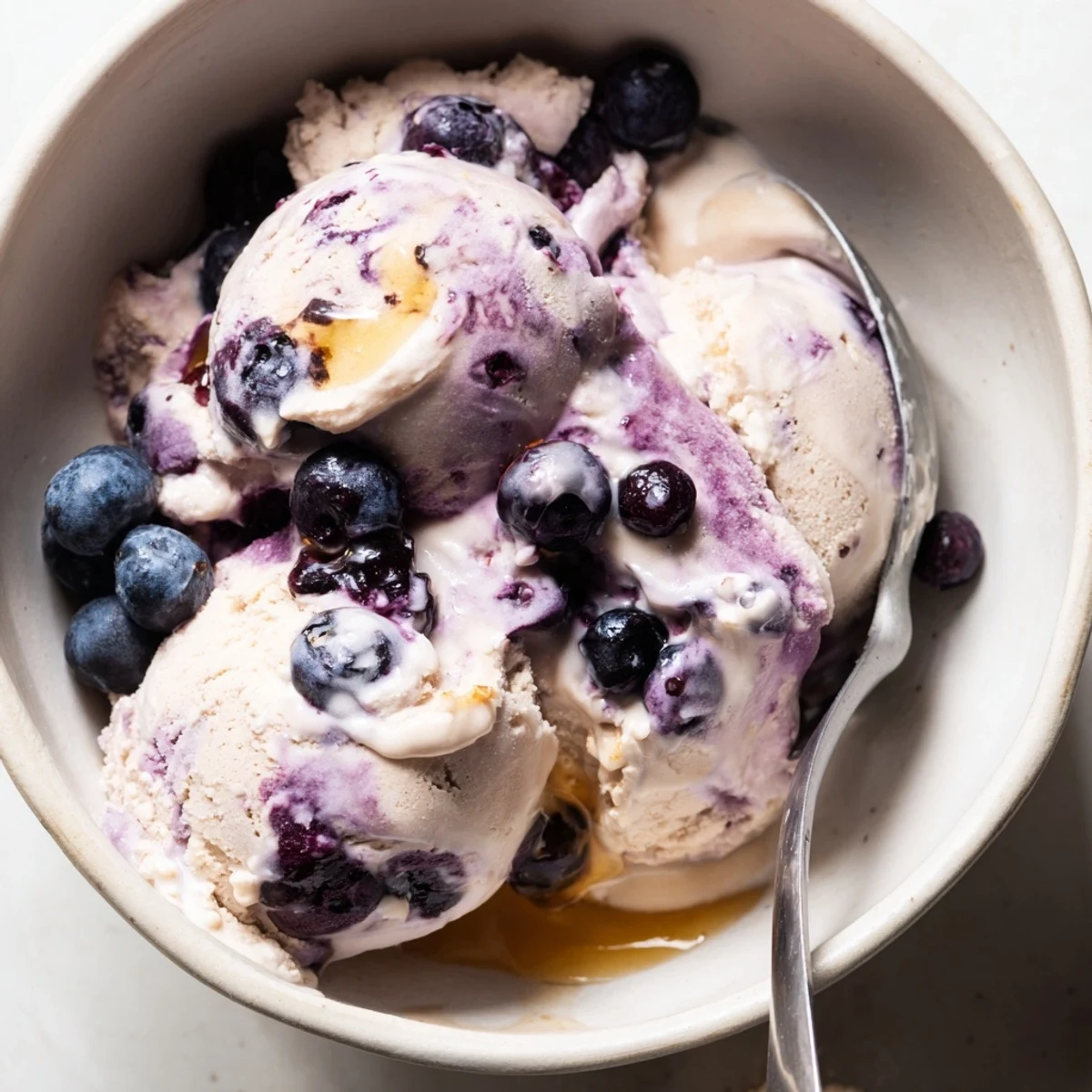 A close-up view of Blueberry Cottage Cheese Ice Cream in a loaf pan, showing a smooth, creamy texture with blueberry swirls.