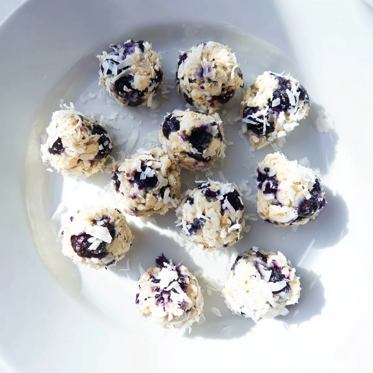 Lemon Blueberry Cottage Cheese Protein Bites stacked high on a rustic wooden serving board.