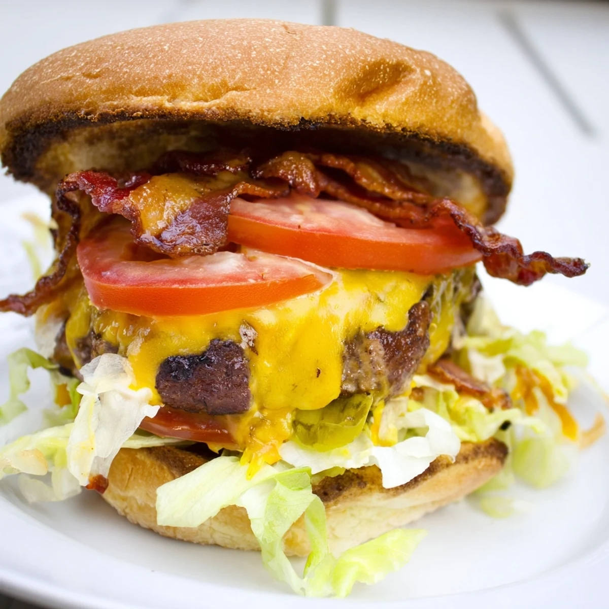 Two Crack Burgers with juicy beef patties, bacon, and ranch dressing served with fries on a wooden board.