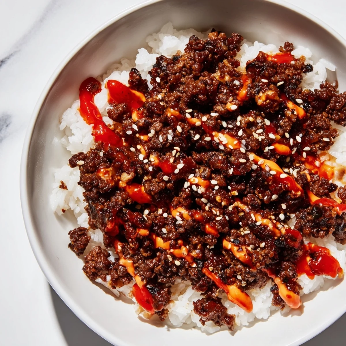 In this Korean Beef Bowl with Spicy Mayo, savory beef, crunchy carrots, cucumbers, and green onions fill a white bowl.