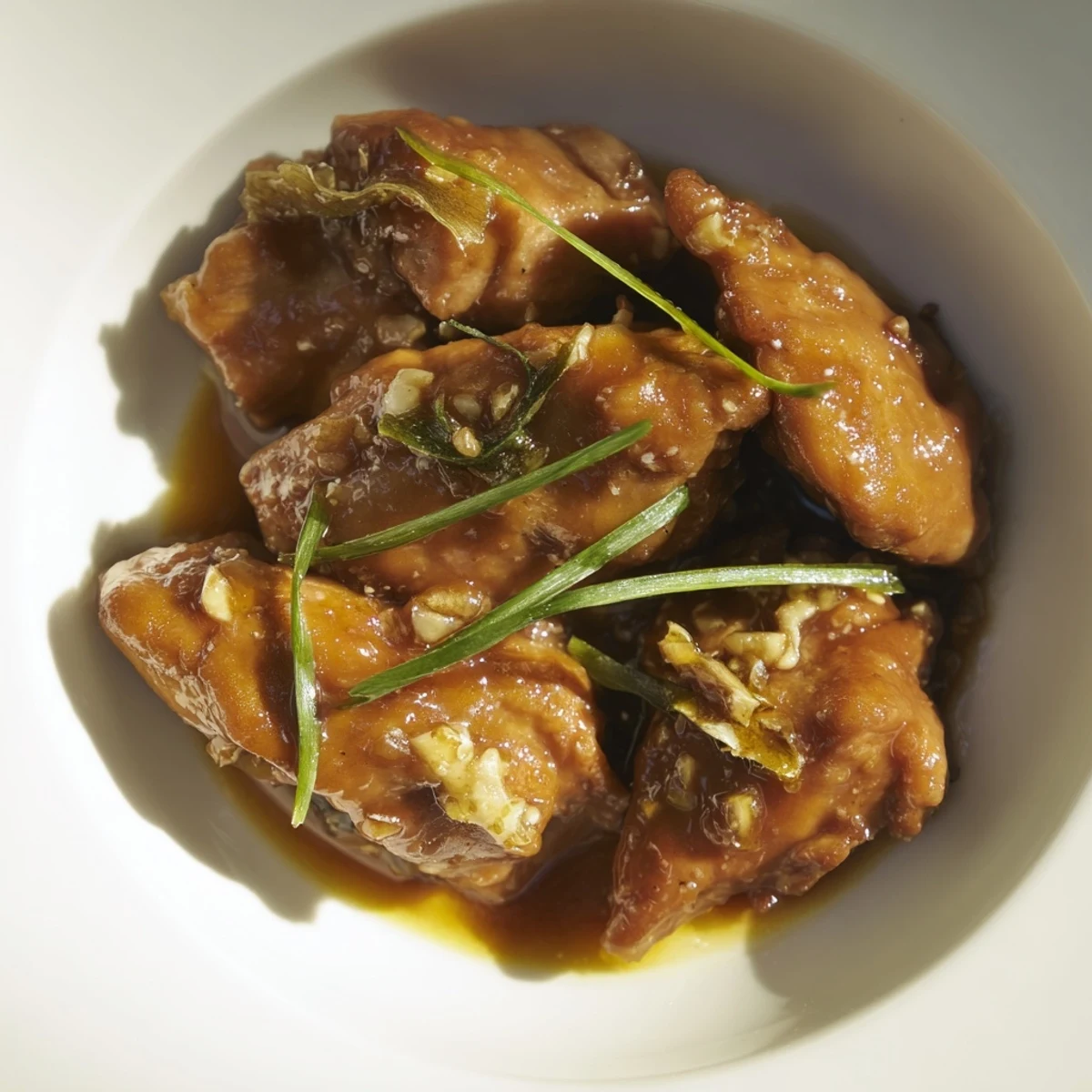 Plate of sweet savory Mongolian chicken served over steamed white rice with scallions