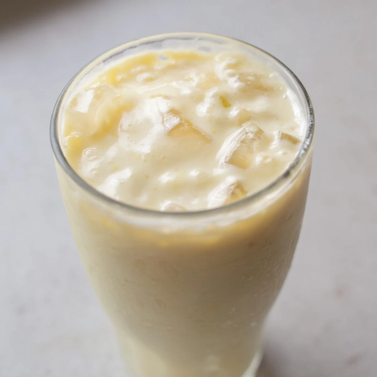 Tropical durian smoothie topped with ice showcasing smooth velvety pale yellow texture