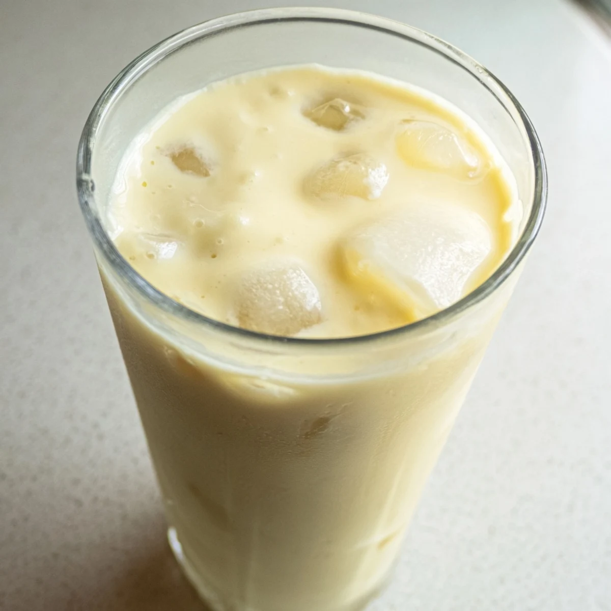 Fresh durian smoothie poured into chilled glasses with frothy coconut milk layer