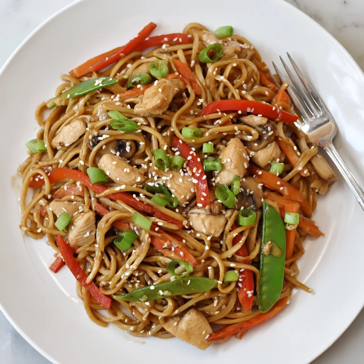 Easy Crockpot Chicken Lo Mein piled in a bowl with tender chicken pieces and colorful vegetables