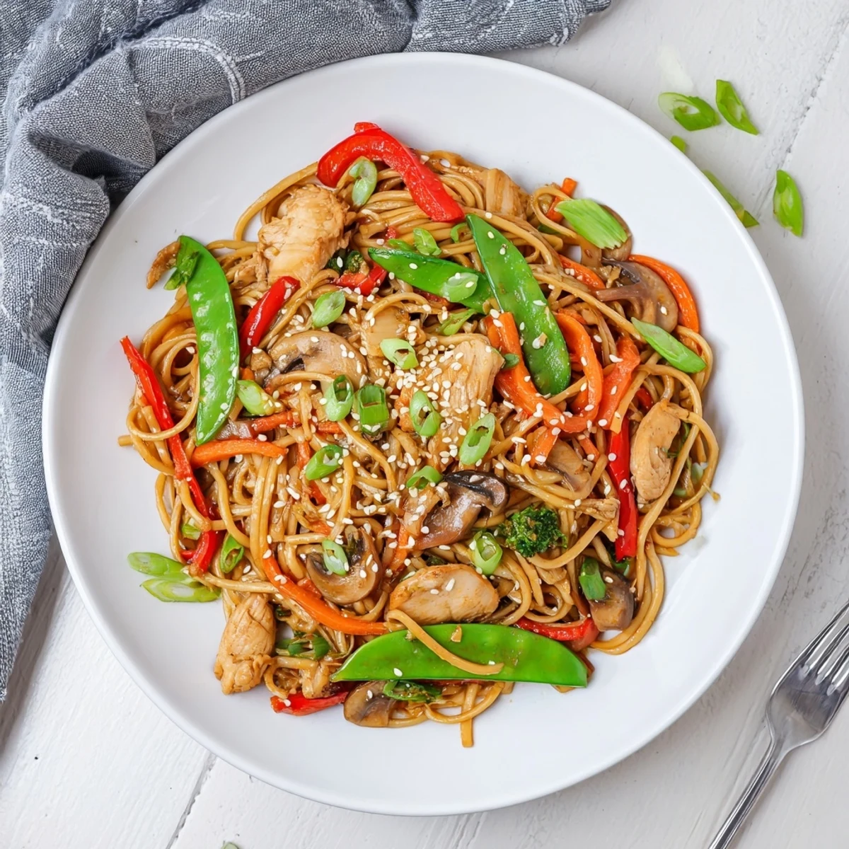Slow cooker chicken lo mein garnished with sesame seeds and fresh green onions on top