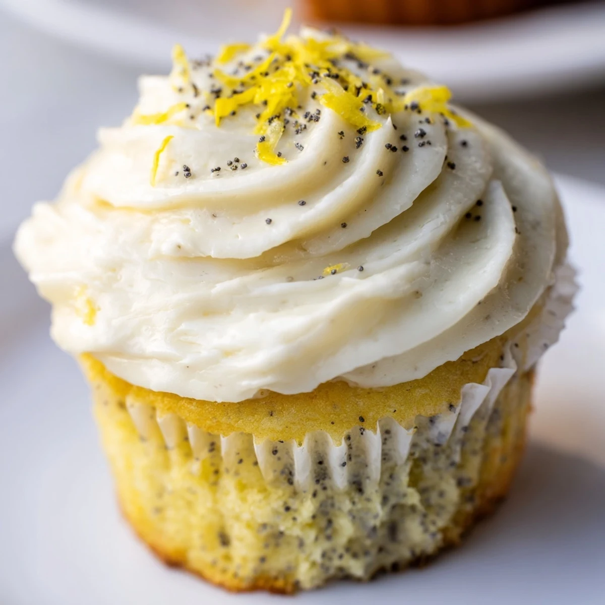 Moist lemon poppy seed cupcakes with speckled batter and swirls of tangy lemon frosting