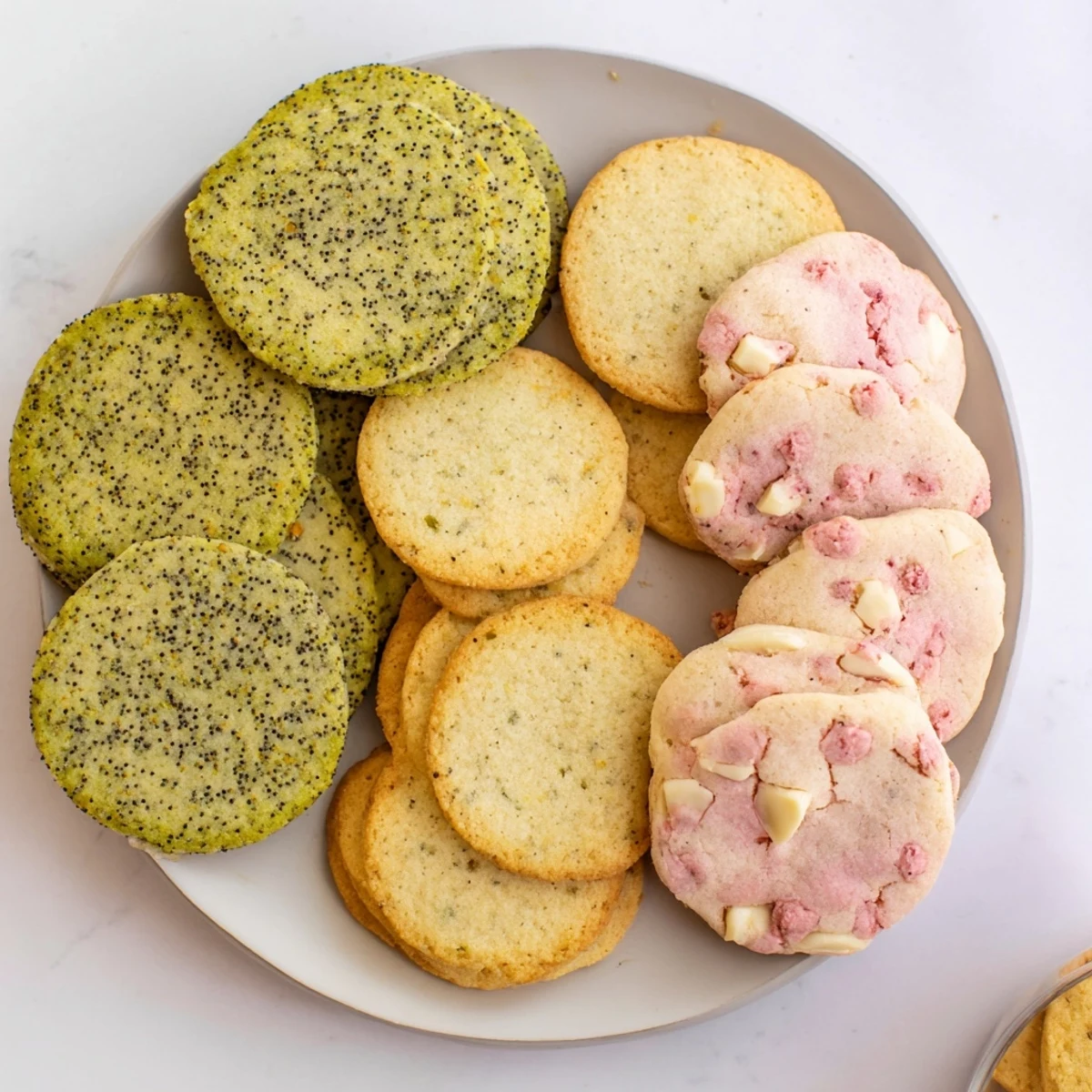Baked spring cookie collection showcasing three varieties with fresh lemon zest, crushed strawberries, and chopped almonds visible on surface