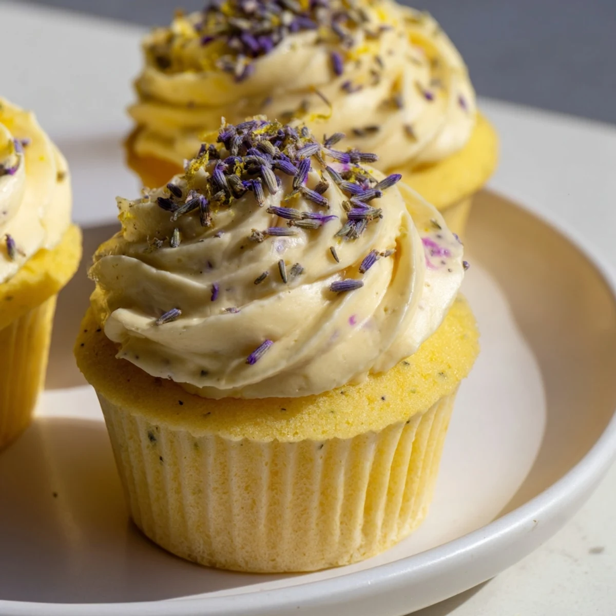 Golden Fresh and Fluffy Lemon Lavender Cupcakes with zesty lemon zest garnish, swirled with buttercream frosting on a rustic wooden board.