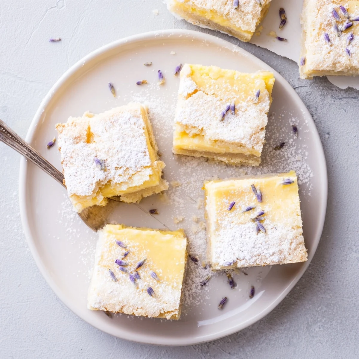 Golden lavender lemon cream bars with white powdered sugar dusting on a serving plate