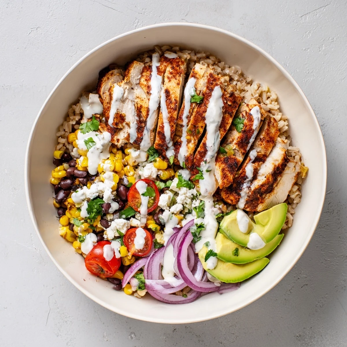 Vibrant protein packed street corn chicken bowl drizzled with tangy yogurt lime dressing and topped with cotija cheese