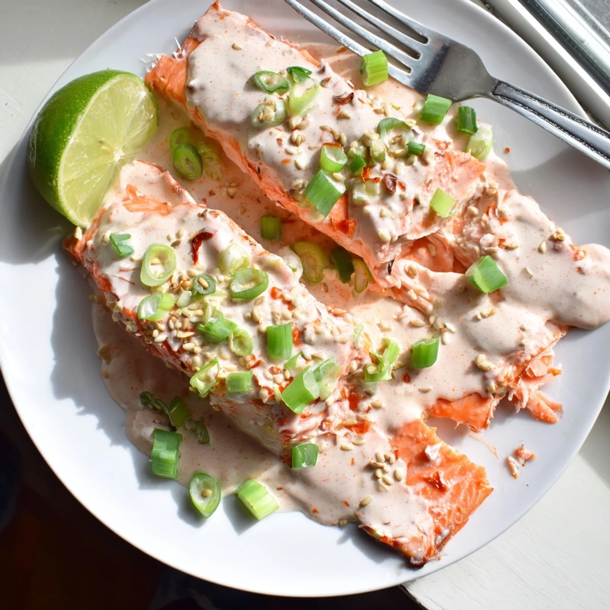 Flaky baked salmon drizzled with spicy Bang Bang sauce served with fresh lime wedges