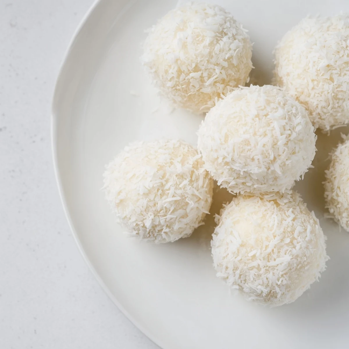 White no bake Easter bunny coconut tails dusted with powdered sugar on white plate