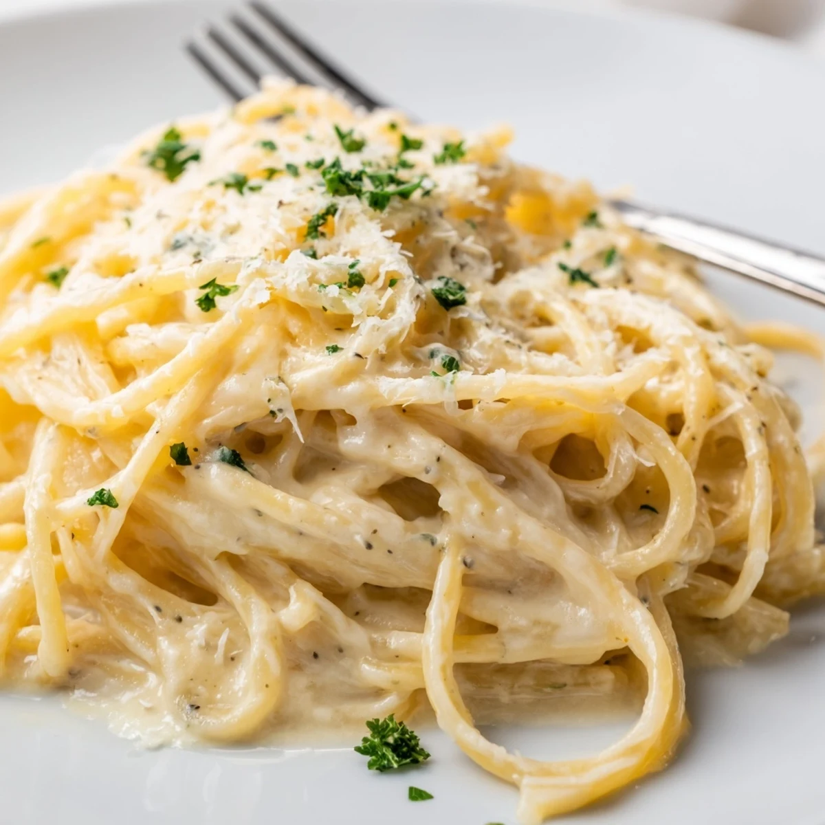 Steaming plate of cheesy garlic Parmesan spaghetti draped in rich white sauce