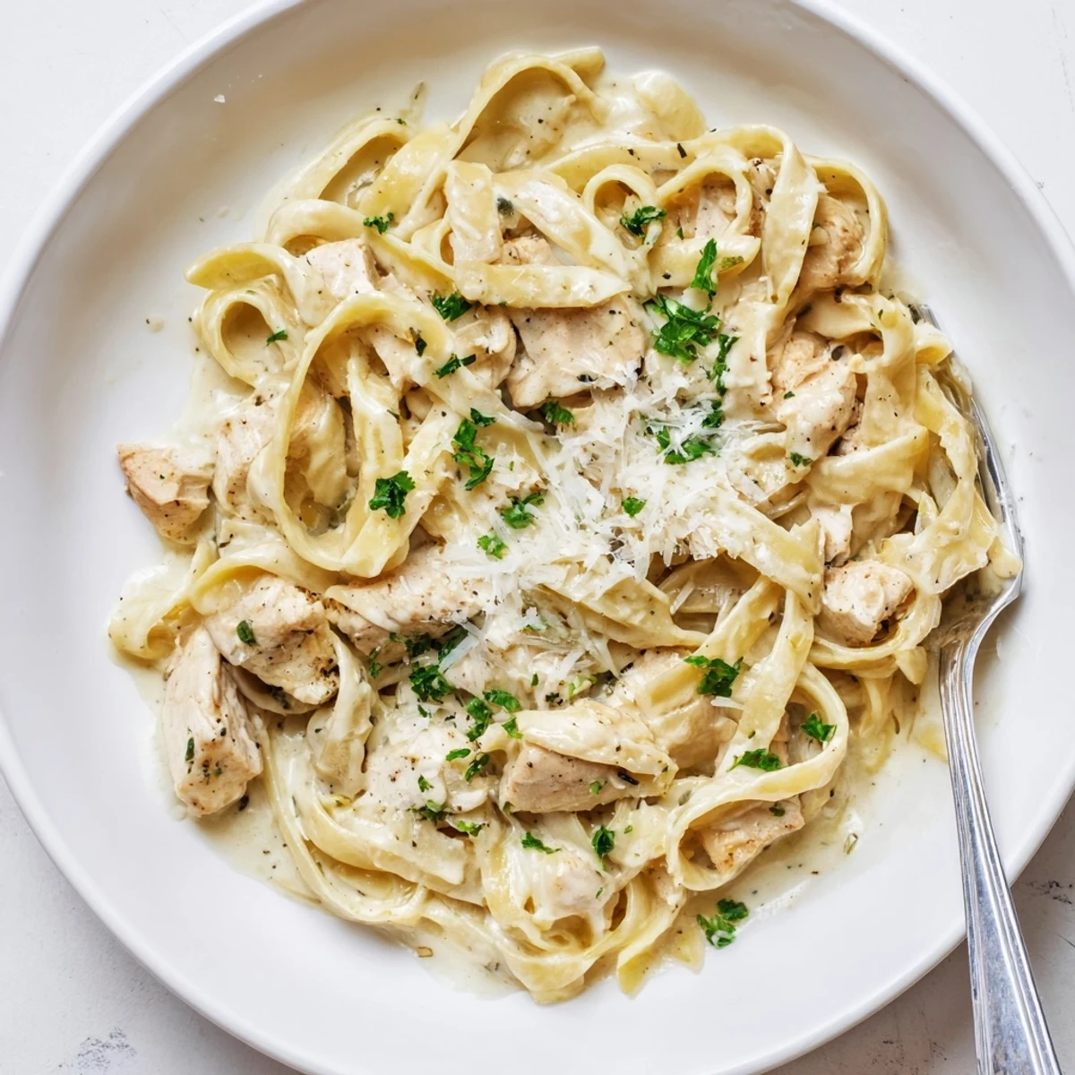 Golden brown chicken breast nestled among fettuccine noodles in a luscious white cream sauce