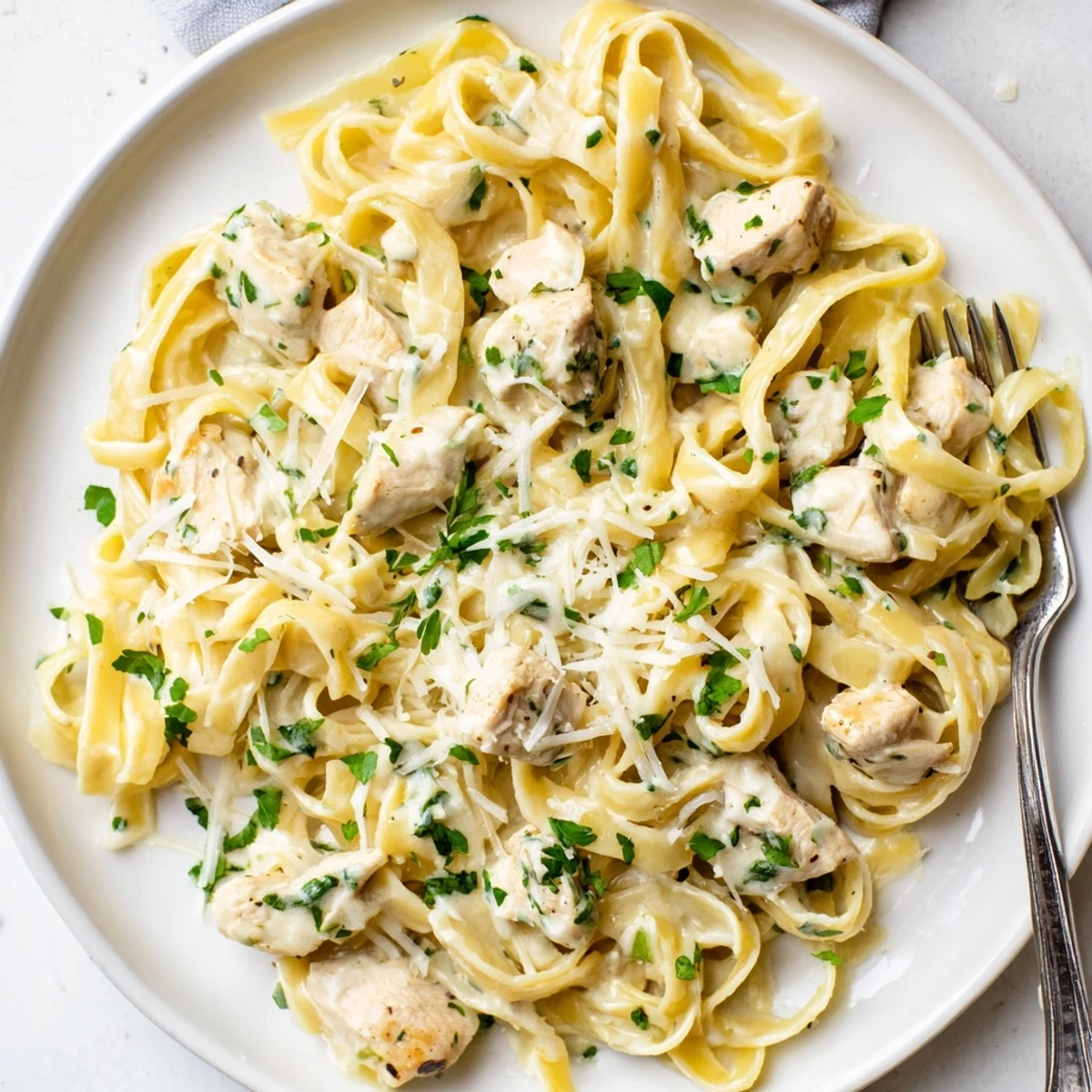 Serving bowl of Instant Pot Chicken Alfredo topped with fresh parsley and extra grated parmesan cheese