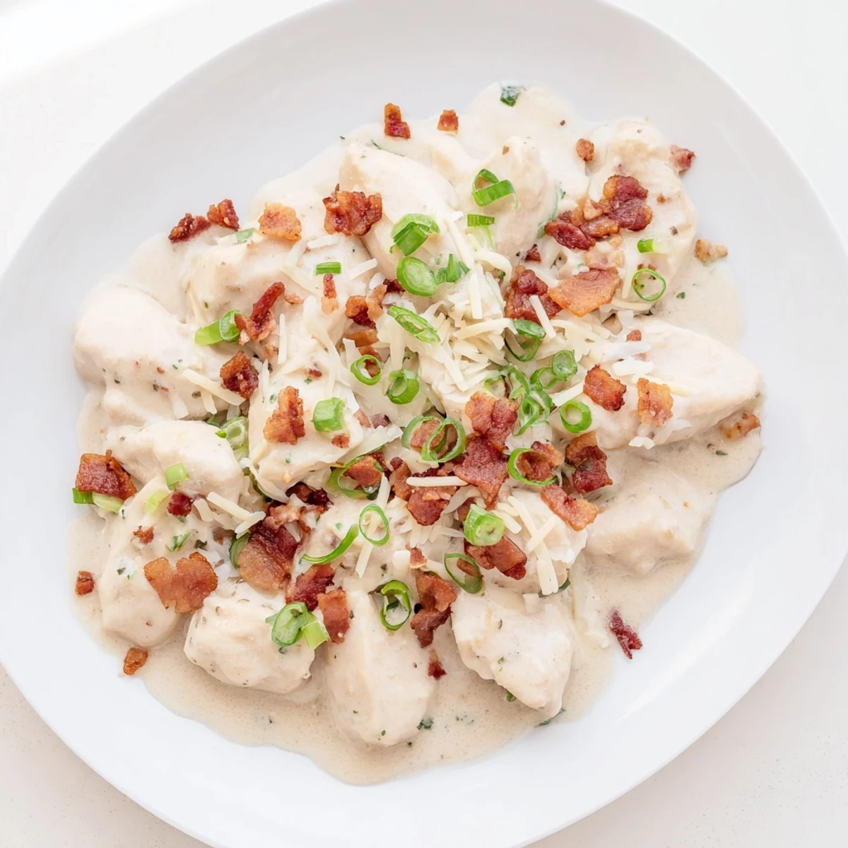 Golden brown Crockpot Million Dollar Chicken topped with melted mozzarella and crispy bacon crumbles