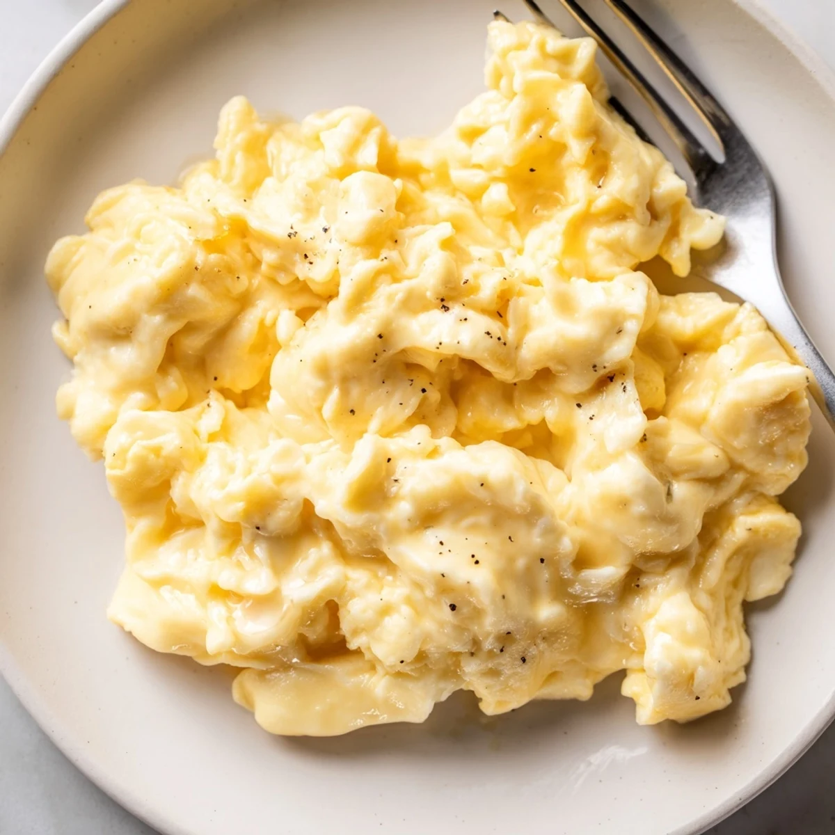 Creamy scrambled eggs with soft golden curds piled on a warm breakfast plate