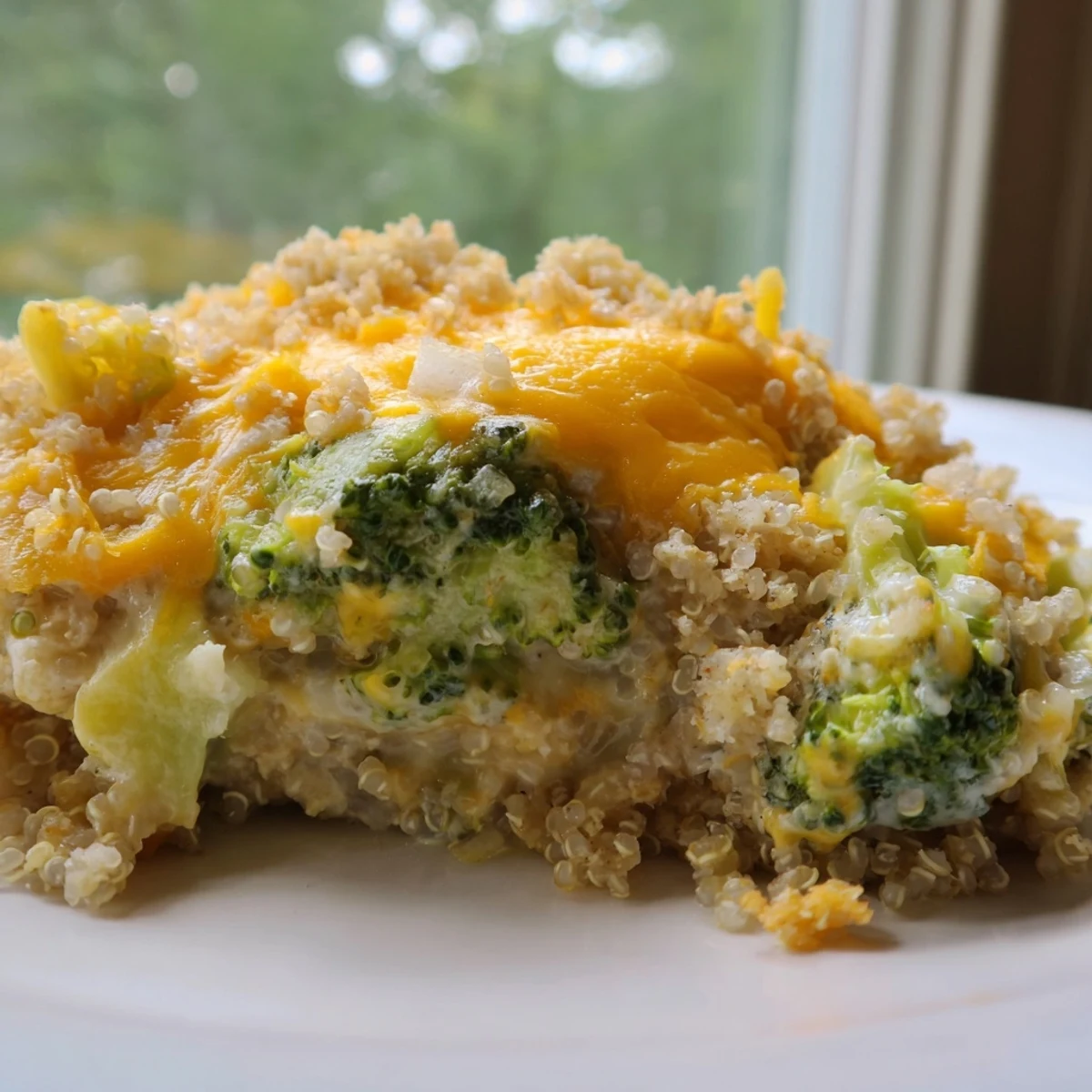 Golden bubbly creamy broccoli quinoa casserole fresh from the oven with melted cheddar topping