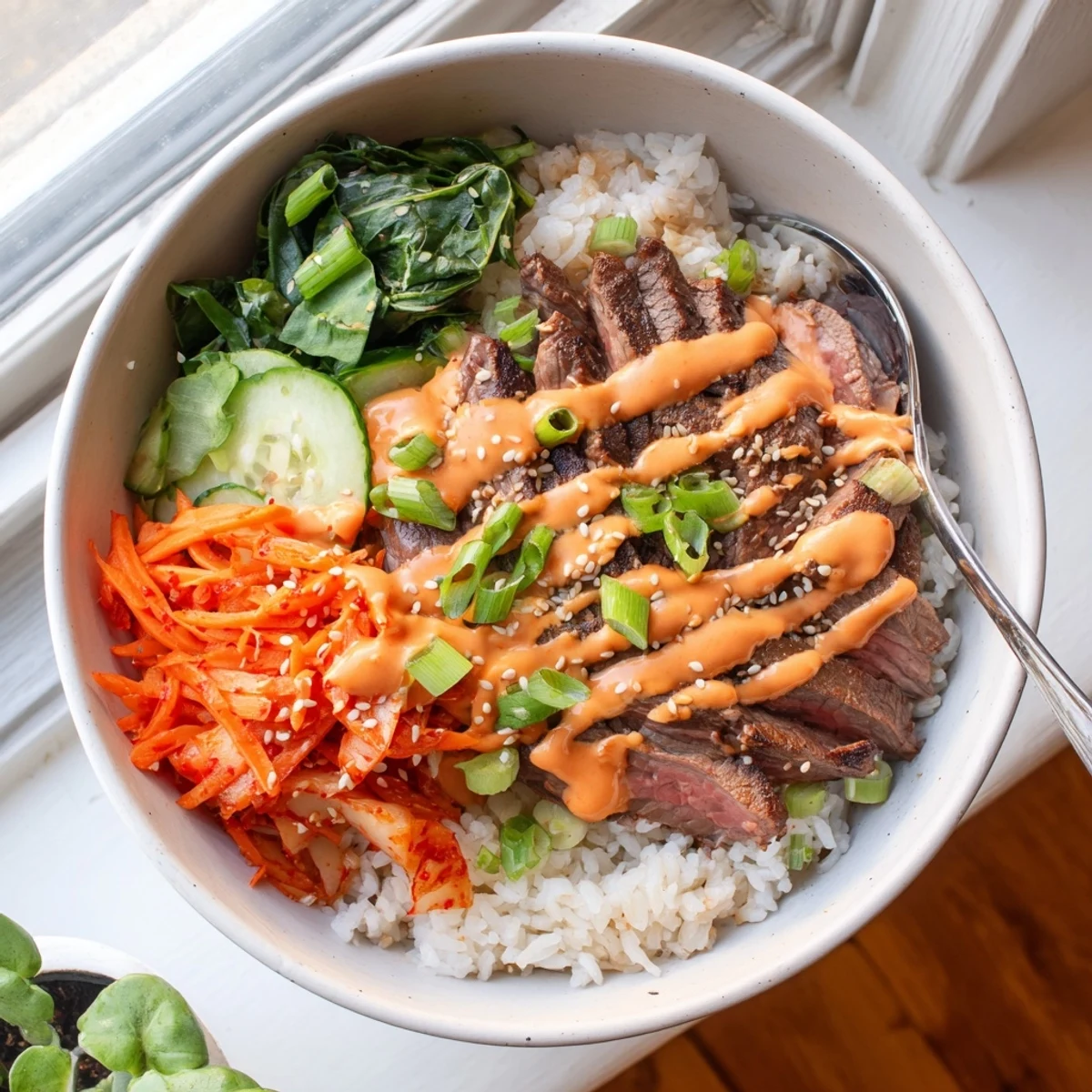 A generous Korean BBQ steak rice bowl topped with kimchi and a bold creamy sauce.