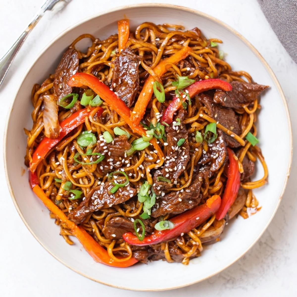 Wok-tossed Sticky Beef Noodles piled high, chewy noodles coated in honeyed glaze