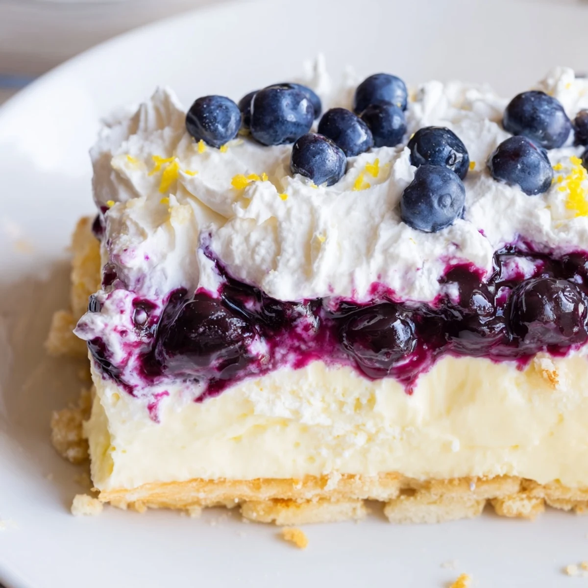 Slice of Lemon Blueberry Lasagna Recipe showing buttery crust and fluffy whipped topping  