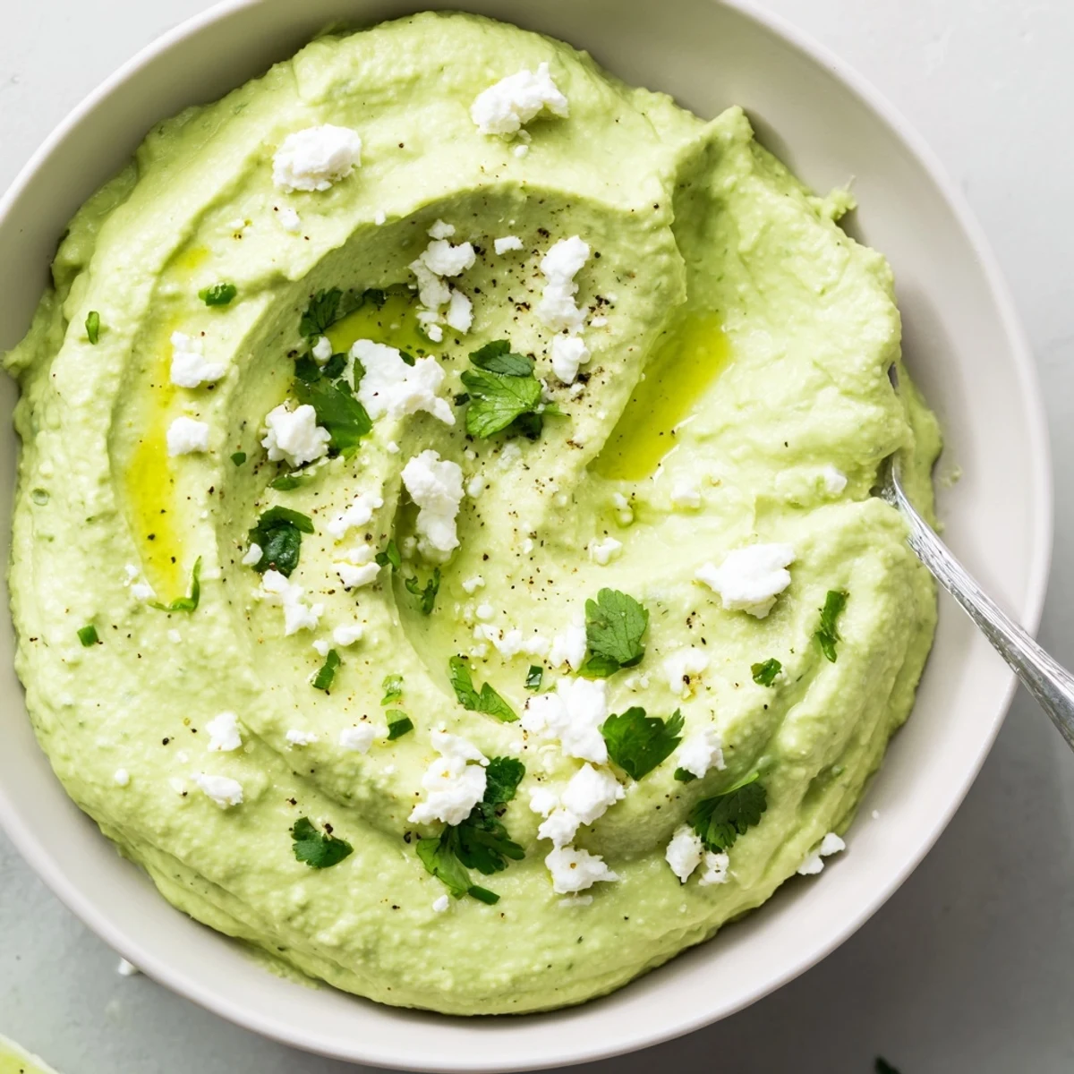 Whipped Creamy Avocado Feta Dip served with crisp vegetable sticks and lime wedge