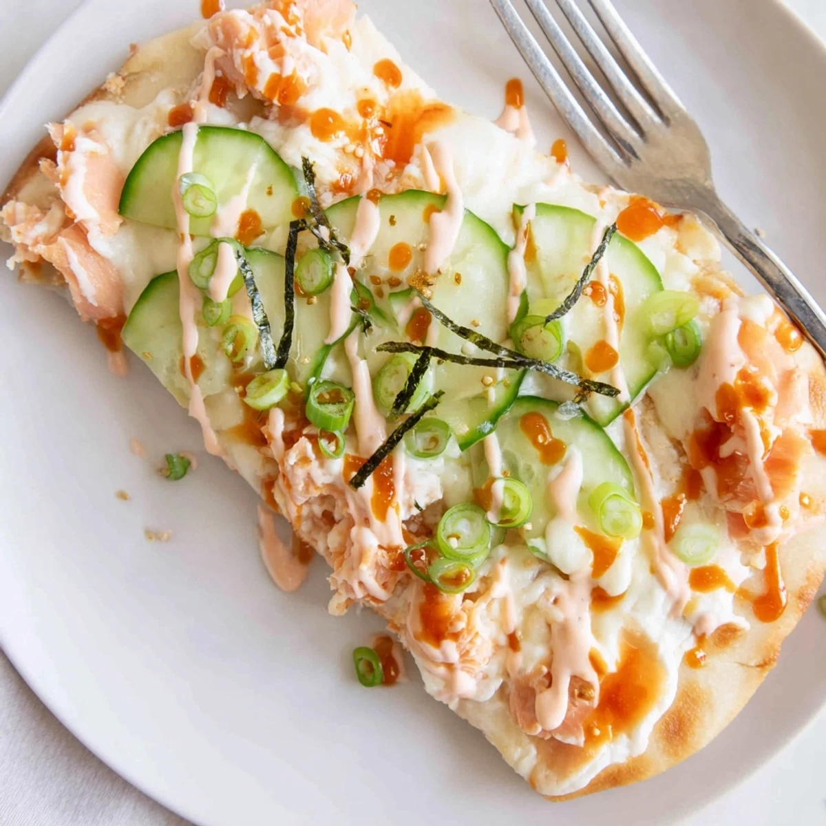 Baked on warm naan, Salmon Sushi Bake Flatbread Pizza With Spicy Drizzle, bright avocado  