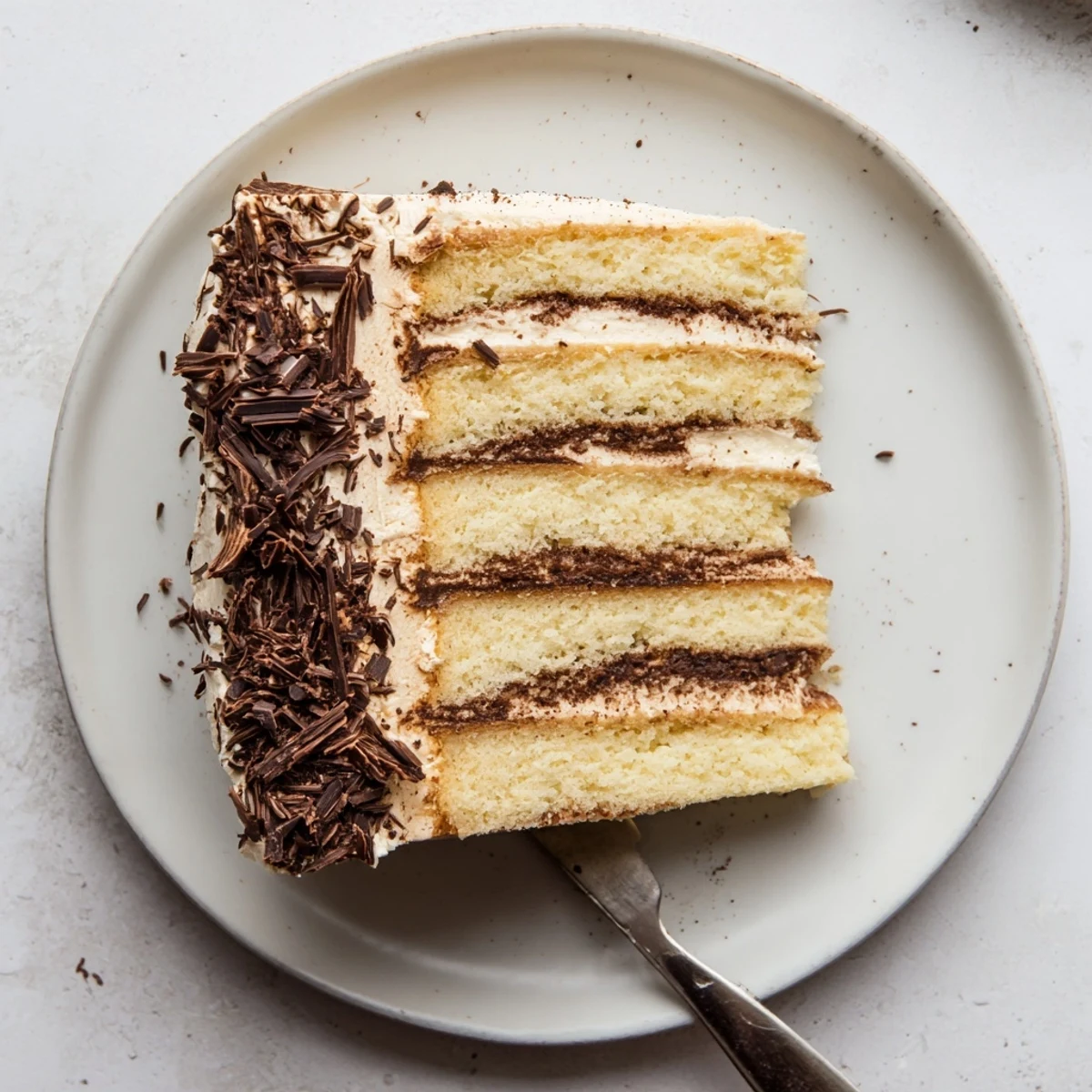 Tiramisu cake with four coffee-soaked layers and creamy mascarpone filling dusted in cocoa
